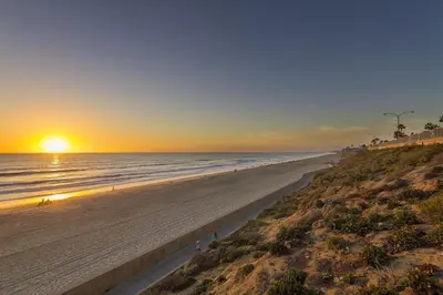 a beach with the sun setting on the ocean at Ocean Views, Across The Street From Beach, Private Patio in Carlsbad
