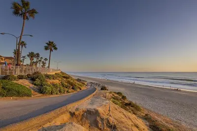 a road leading to a beach with palm trees and the ocean at Ocean View From Private Patio, Steps To Beach, Parking in Carlsbad