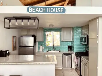 a kitchen with a beach house sign above a counter at OCEAN FRONT Beach HOUSE! Private Stairs to SAND! in Laguna Beach