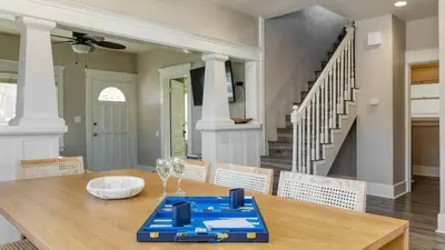 a dining room with a table and chairs and a staircase at Sea Sight by AvantStay Walk to Newport Beach in Newport Beach