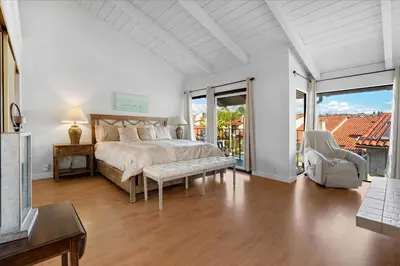 a white bedroom with a bed and a balcony at Carlsbad Hideway Pool Spa in Carlsbad