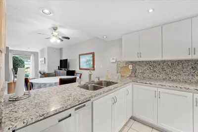 a kitchen with white cabinets and a living room at Carlsbad Hideway Pool Spa in Carlsbad