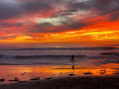 a person standing in the ocean at sunset at Newly Renovated 3BR Modern Apt in Heart of Ocean Beach in San Diego