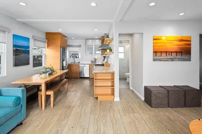 a kitchen and living room with a table and a blue couch at Newly Renovated 3BR Modern Apt in Heart of Ocean Beach in San Diego