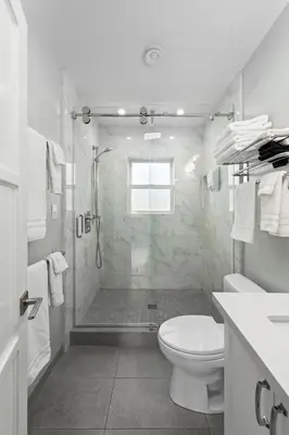 a white bathroom with a shower and a toilet at Modern Luxury 2BR Apt in Heart of Ocean Beach in San Diego