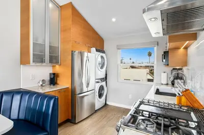 a kitchen with a stainless steel refrigerator and wooden cabinets at Modern Luxury 2BR Apt in Heart of Ocean Beach in San Diego
