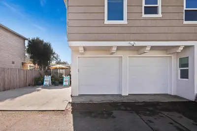 a house with white garage doors in a driveway at 7BD Family, Event Friendly, 2 blocks to Beach, Boardwalk in San Diego