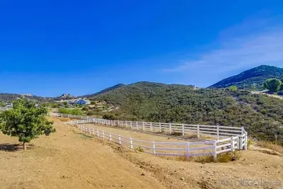 a white fence on top of a hill with mountains at Private Home on 10 Acres - Heated Salt Pool & Jacuzzi, Mountain & City Views, Horseshoes, Basketball, BBQ, Golf Putting, Foosball, Croquet, Bose Stereo, White Cotton Bedding - Hilltop Hacienda, Pool Heat Optional in Jamul
