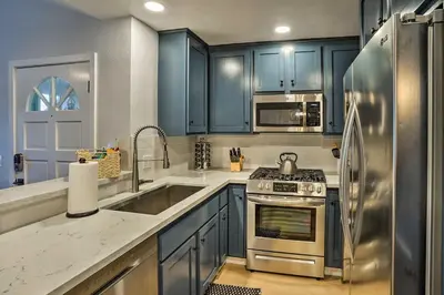 a kitchen with blue cabinets and a stainless steel refrigerator at Cozy-Chic Condo Walk to Beach and Park! in Dana Point