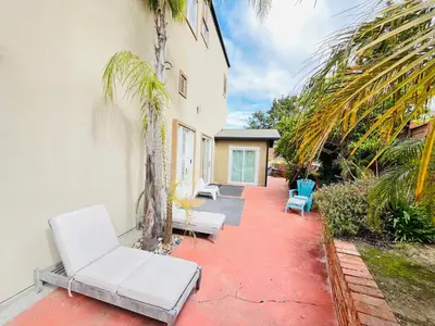 a patio with white chairs and palm trees next to a building at Private Room0 Own Bath Own Entry Shared Kitchen Walk to UCSD in San Diego