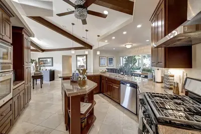 a large kitchen with wooden cabinets and a ceiling fan at Elevado Hills Family Getaway ~ Pool ~ Games ~ Pkg! in Vista