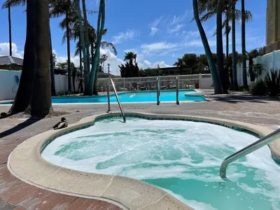 a hot tub in a courtyard with palm trees at Ocean View Luxury Condo Oceanfront and Pool in San Diego