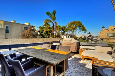 a patio with a wooden table and chairs on a roof at 313 E Bay Ave B in Newport Beach