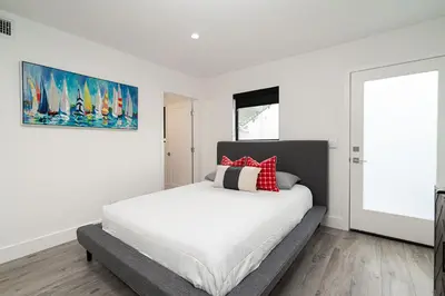 a white bedroom with a bed with red pillows at Pier to Pier in Newport Beach