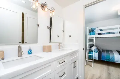 a white bathroom with two sinks and a bunk bed at Upper West Newport in Newport Beach