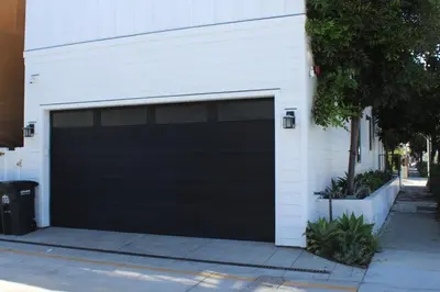a black garage door on the side of a house at Upper West Newport in Newport Beach