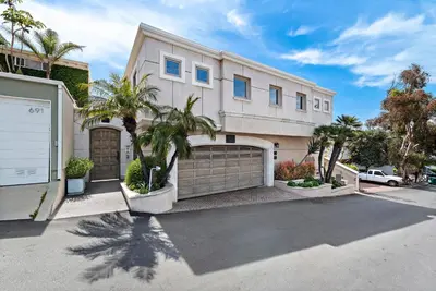 a large white house with a garage and palm trees at Villa Calypso in Laguna Beach