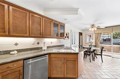 a kitchen with wooden cabinets and a dining room with a table at Villa Calypso in Laguna Beach