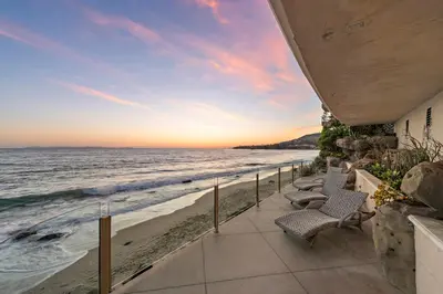 a patio with chairs on the beach at sunset at Villa Calypso in Laguna Beach